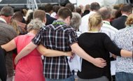 Families who lost loved ones hold each other during a remembrance service in Hagley Park in Christchurch on February 22, 2012, one year after a 6.3 quake hit New Zealand's second largest city