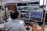 A trader looks at screens showing stock exchange share index in Paris. European stock markets fell and the euro slipped against the dollar in early cautious trade amid lingering eurozone debt concerns despite Greece's new huge bailout. 